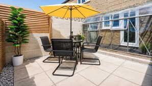 An outdoor patio with a table and chairs, a yellow umbrella, and a potted plant. - Beautiful Abode in The Bath Cotswolds (Frome)