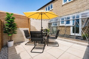 An outdoor patio with a table and chairs, a yellow umbrella, and a potted plant. - Beautiful Abode in The Bath Cotswolds (Frome)