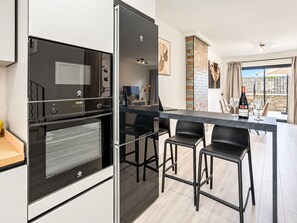 A modern kitchen with a built-in oven and a dining area with bar stools. - Villa Zurbaran Cuatro (Nerja)