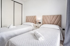 Ein Hotelzimmer mit zwei Betten, einem Nachttisch, einer Lampe und einem Kleiderschrank.