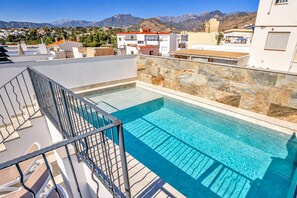 Ein Pool auf dem Dach mit einer Steinmauer und Blick auf die Berge im Hintergrund.