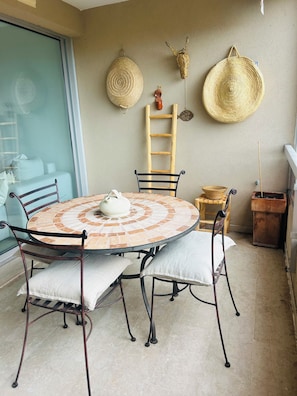 A round table with a mosaic tile top, surrounded by metal chairs with cushions. - The Open Sea (Cassis)
