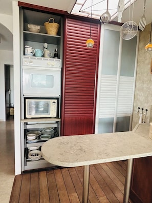 A kitchen with a built-in oven, a red cupboard, and a dining table. - The Open Sea (Cassis)