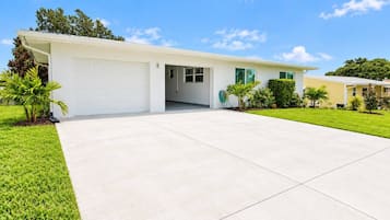 A single-story house with a garage, a front lawn, and a clear sky.