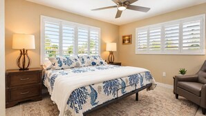 A bedroom with a bed, two bedside tables with lamps, a ceiling fan, and a window with shutters. - Jensen Beach 3BR/3BA Family Retreat + Game Room (Jensen Beach)