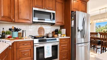 Une cuisine avec des meubles en bois, un réfrigérateur en acier inoxydable, un four à micro-ondes et un four traditionnel.