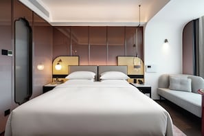 A hotel room with a large bed, two bedside tables, a sofa, and a wall-mounted lamp. - LIAN HOTEL (Deqin)