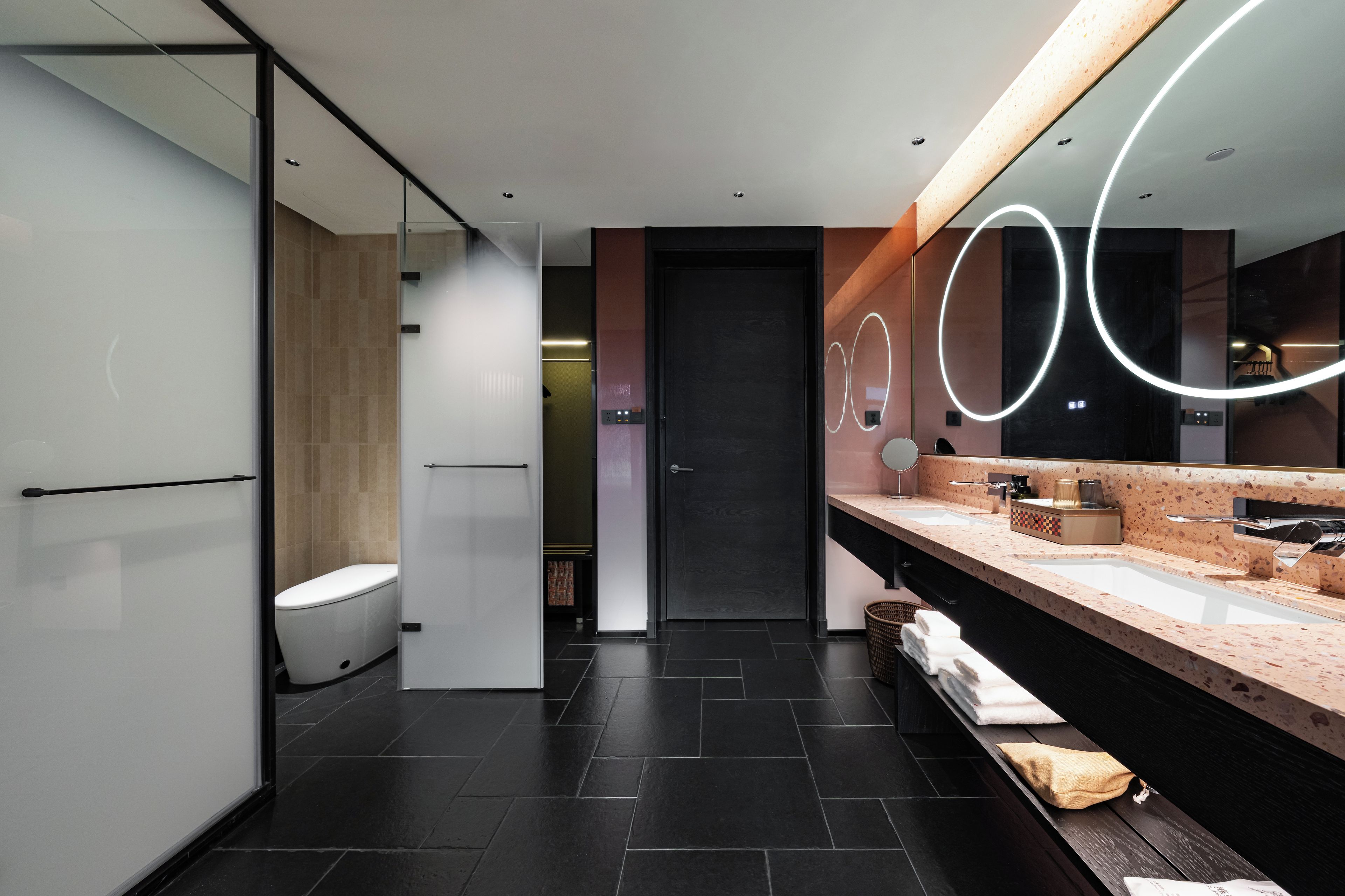 A modern bathroom with a toilet, a sink with a mirror, and a shower area.