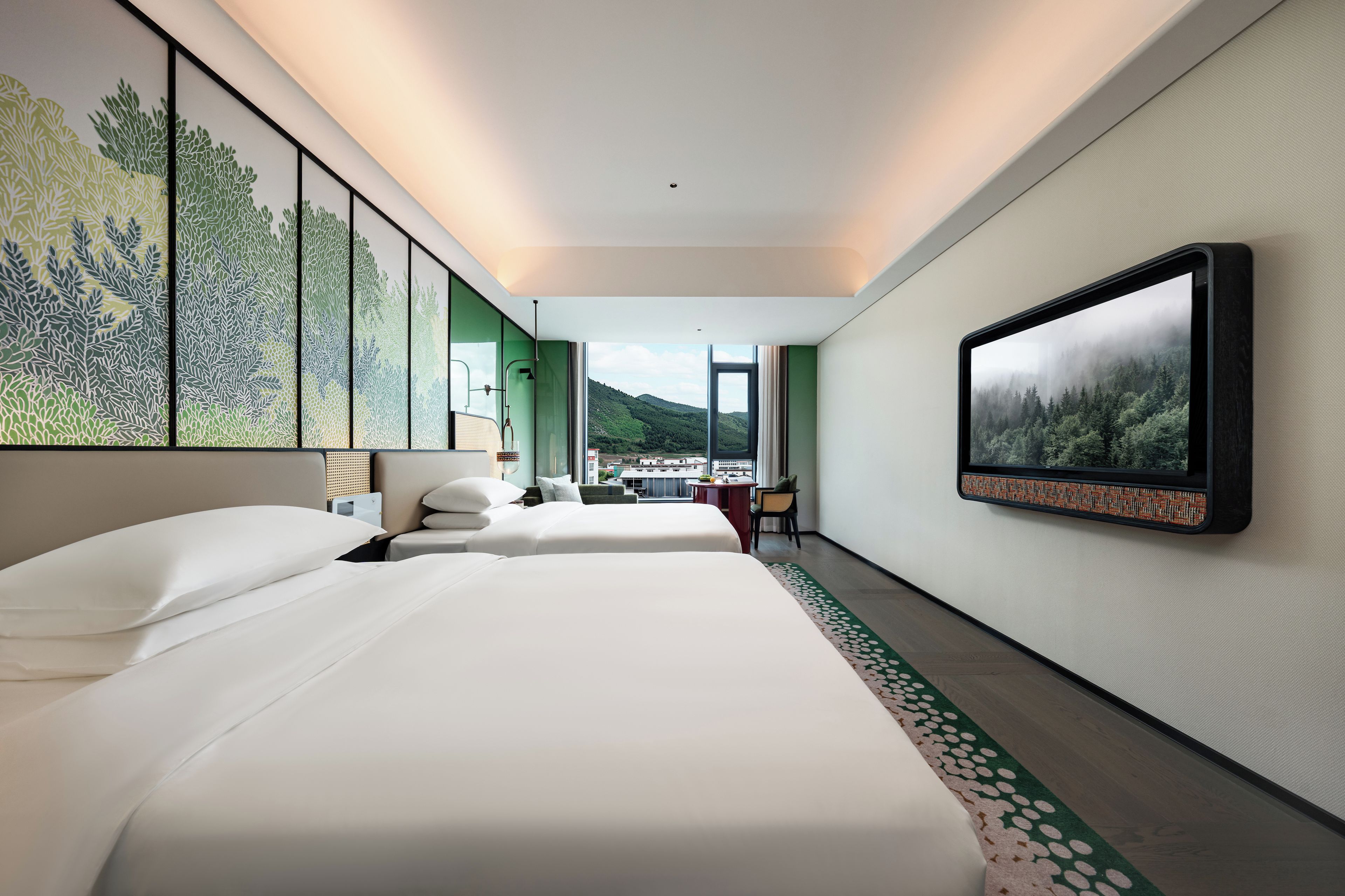 A hotel room with two beds, a large window, and a view of a mountainous landscape.