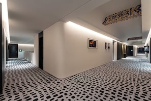 A hallway with patterned flooring, a curved wall, and a ceiling with recessed lighting. - LIAN HOTEL (Deqin)
