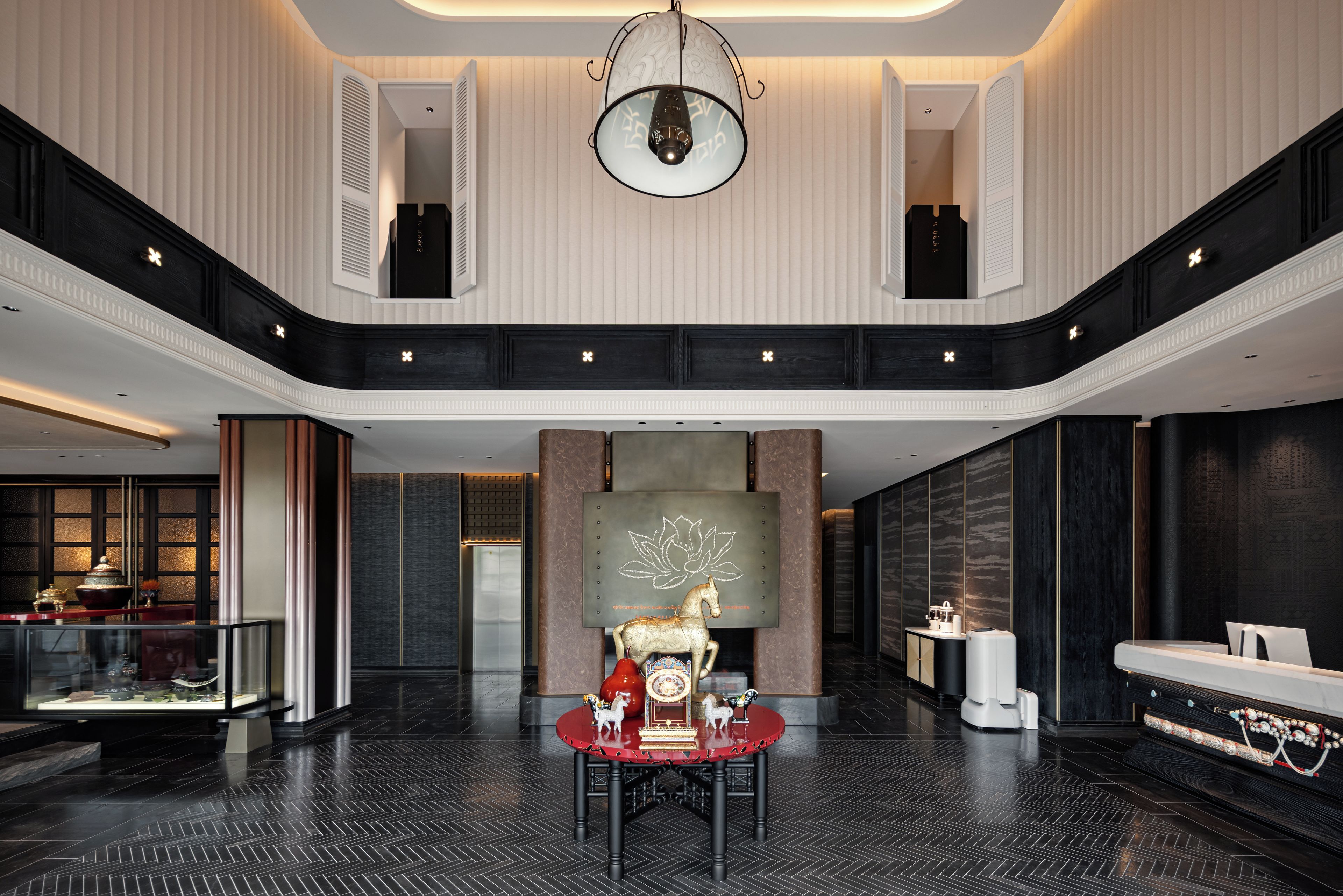 Un vestíbulo amplio con techo alto, una pared decorativa central y una zona de estar con mesa y sillas.