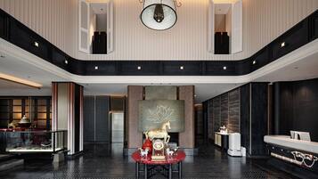 Un'ampia hall con soffitto alto, una parete decorativa centrale e un'area salotto con tavolo e sedie.