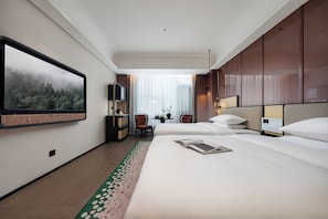 A hotel room with a large bed, a desk, a chair, a television, and a view of a forest through the window. - LIAN HOTEL (Deqin)