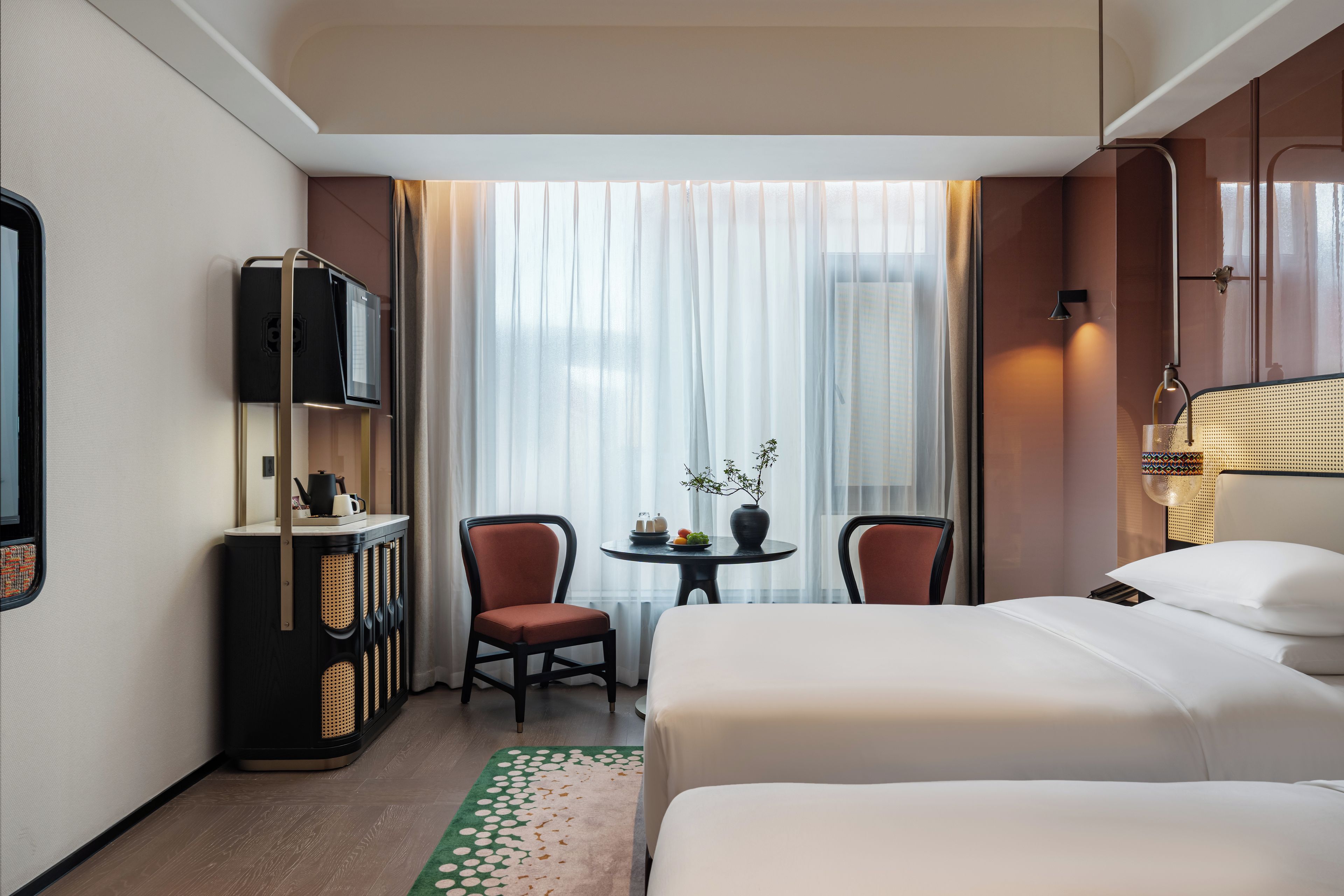 Ein Hotelzimmer mit einem Bett, einem Schreibtisch mit Stuhl, einem Fernseher und einem Fenster mit Vorhängen.