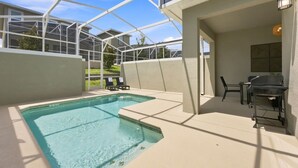A pool area with a glass enclosure, a barbecue grill, and outdoor seating. - ChampionsGate Home: Pool, Disney 15min, Sleeps 13 (Kissimmee)