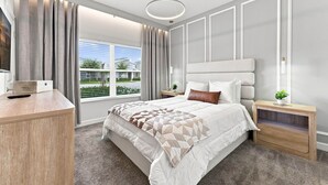 A modern bedroom with a large bed, a bedside table, a nightstand, a built-in bench, a window with curtains, and a ceiling light. - ChampionsGate Home: Pool, Disney 15min, Sleeps 13 (Kissimmee)