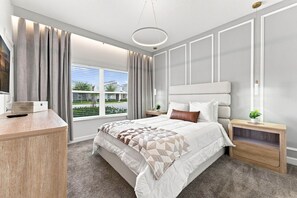 Un dormitorio moderno con una cama grande, una mesita de noche, un banco empotrado, una ventana con cortinas y una lámpara en el techo.
