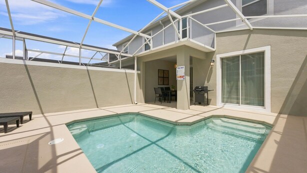 A swimming pool with a covered patio area, a table, and chairs. - ChampionsGate Home: Pool, Disney 15min, Sleeps 13 (Kissimmee)
