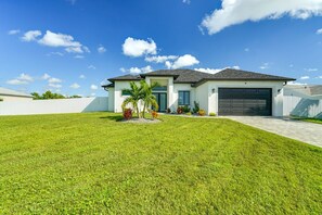 A modern two-story house with a garage, surrounded by a well-maintained lawn and a white fence. - Private Pool & Fun-Filled 4BR Cape Coral Retreat (Cape Coral)