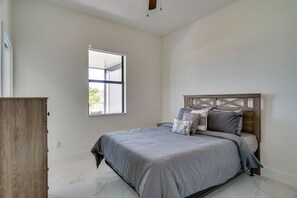 A bedroom with a bed, a window, and a wooden wardrobe. - Private Pool & Fun-Filled 4BR Cape Coral Retreat (Cape Coral)