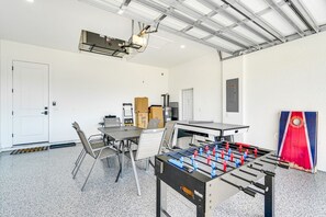 A room with a foosball table, a ping pong table, and a projector mounted on the ceiling. - Private Pool & Fun-Filled 4BR Cape Coral Retreat (Cape Coral)