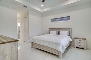 A bedroom with a bed, bedside table, and a window. - Private Pool & Fun-Filled 4BR Cape Coral Retreat (Cape Coral)