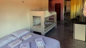 A room with bunk beds, a desk, chairs, and a bed with towels. - POUSADA ROSA MISTICA (Paracuru)