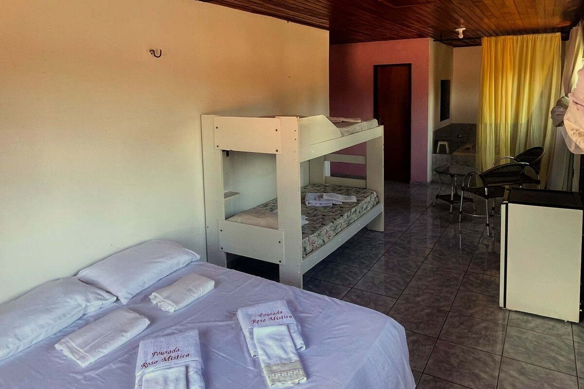 A room with bunk beds, a desk, chairs, and a bed with towels.