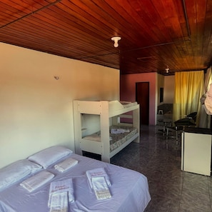 A room with bunk beds, a desk, chairs, and a bed with towels. - POUSADA ROSA MISTICA (Paracuru)
