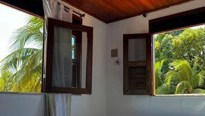 Una habitación con cama, un banco y ventanas con vistas a la vegetación.
