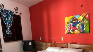 A bed with a wooden frame, white bedding, and a colorful painting on the wall. - POUSADA ROSA MISTICA (Paracuru)