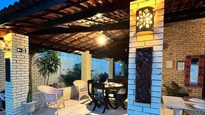 Un patio al aire libre con una zona de estar techada, una mesa y plantas en macetas.