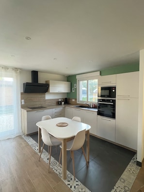 Une cuisine moderne avec une table à manger, des chaises et des appareils électroménagers intégrés.