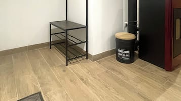 Une pièce avec une étagère en métal noir, une poubelle noire et un plancher en bois.