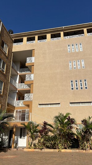 Ein mehrstöckiges Gebäude mit Balkonen, einer flachen Dachterrasse und einem Innenhof mit Pflanzen.