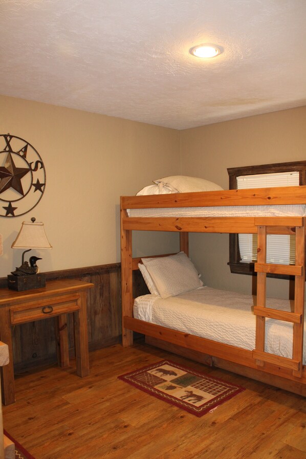 A bunk bed with a headboard, a desk with a lamp, and a wall clock.