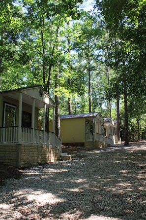 A row of cabins with a gravel path leading to them, surrounded by trees.