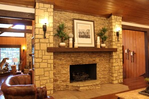 A stone fireplace with a framed picture above it, flanked by wall-mounted lights, and a wooden door to the right.