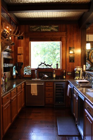 A kitchen with wooden cabinets, a stainless steel sink, and a window with a view of greenery.