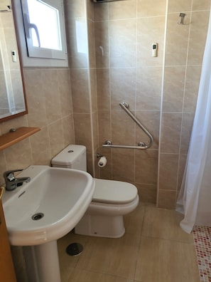 Et badeværelse med toilet, håndvask og bruser.