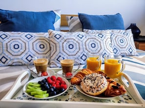 A breakfast tray with croissants, berries, and juice on a bed with patterned pillows. - Vrbo Property (Adeje)
