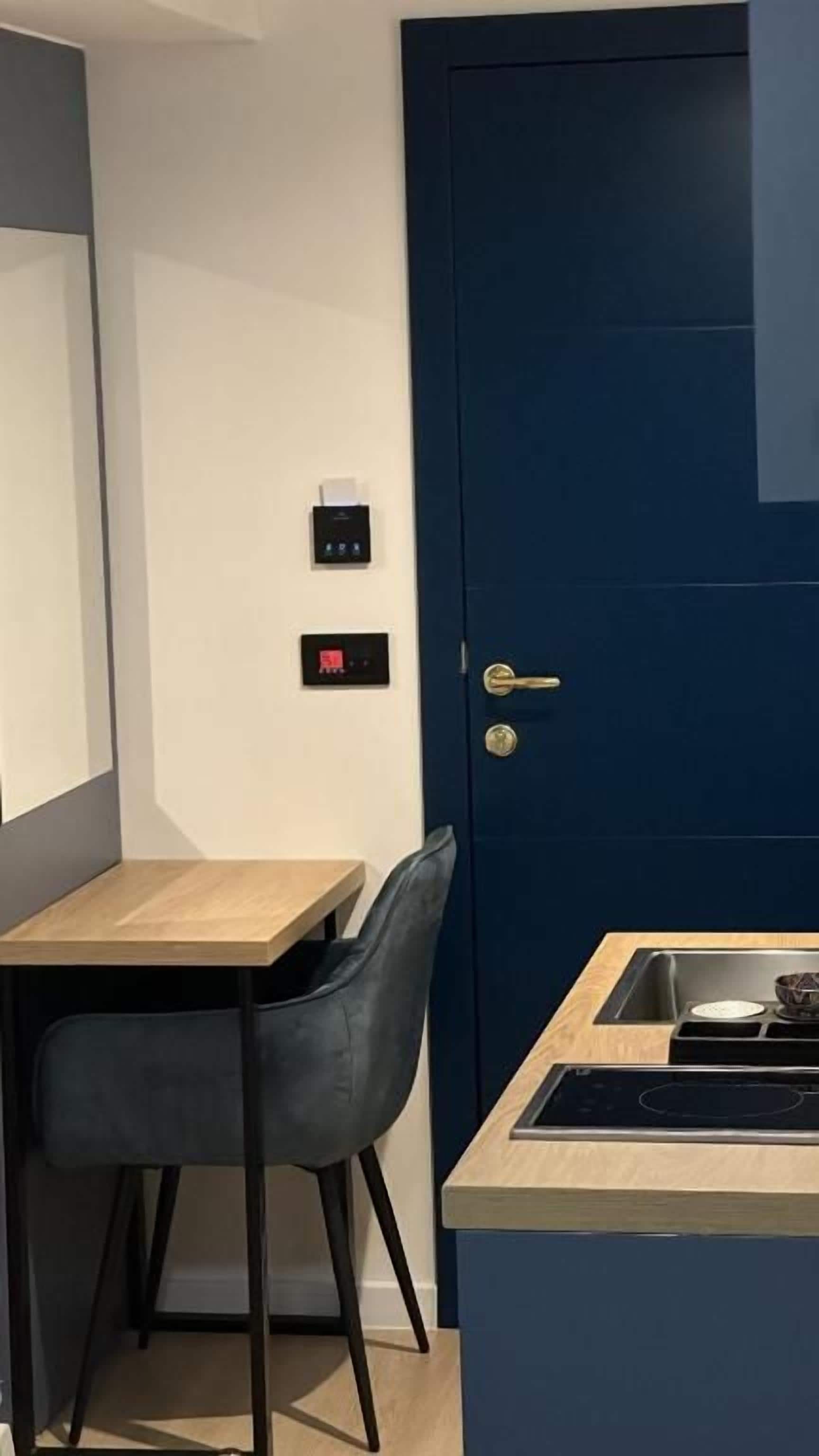 Cozinha compacta com porta azul, uma pequena mesa de jantar e uma cadeira.