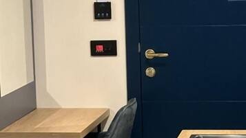 Cozinha compacta com porta azul, uma pequena mesa de jantar e uma cadeira.