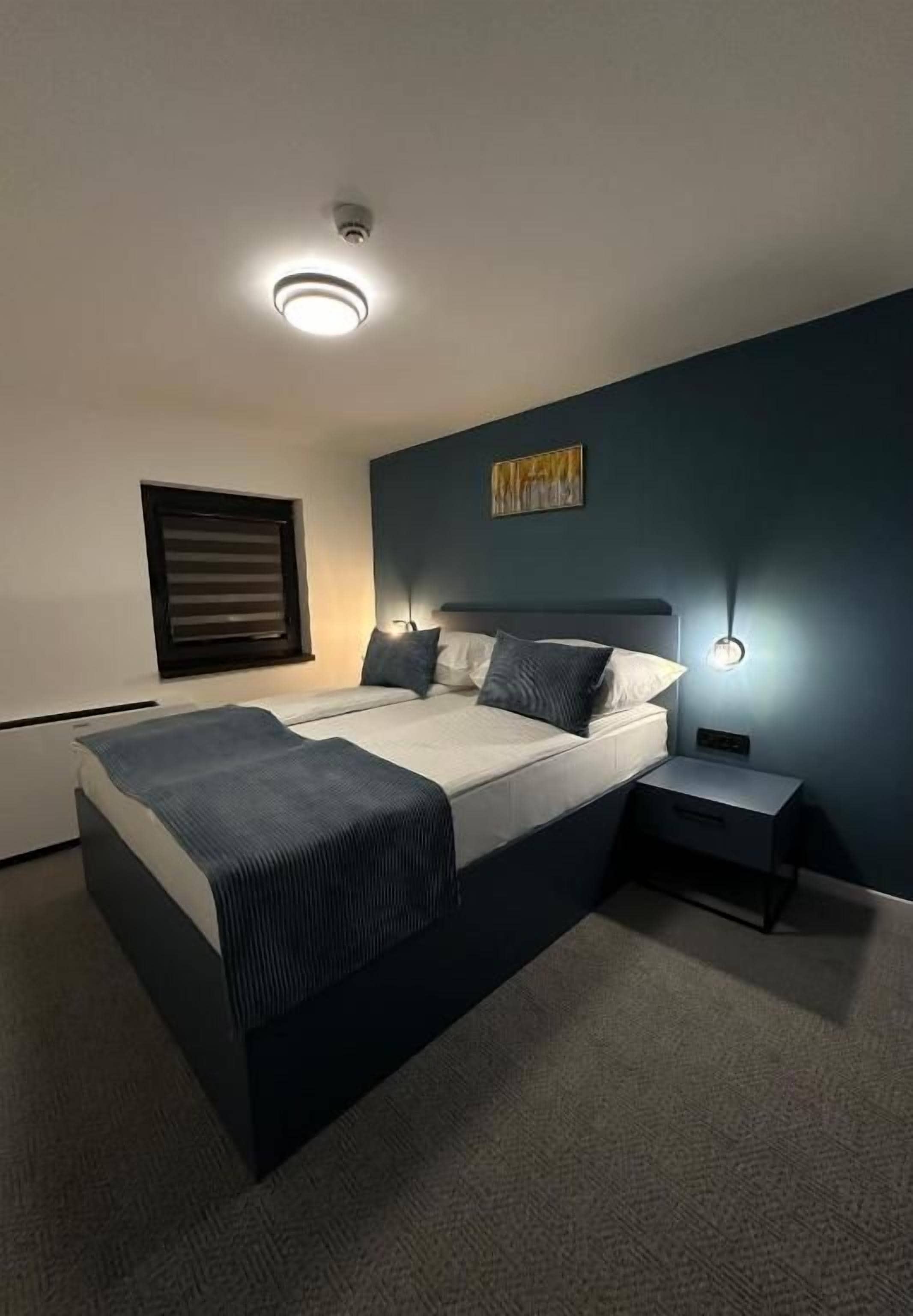 A modern bedroom with a bed, bedside tables, and a ceiling light fixture.