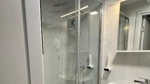 A modern bathroom with a glass-enclosed shower, a white sink, and a mirror above the sink. - Alinar Oasis Budget Hotel (Sarajevo)
