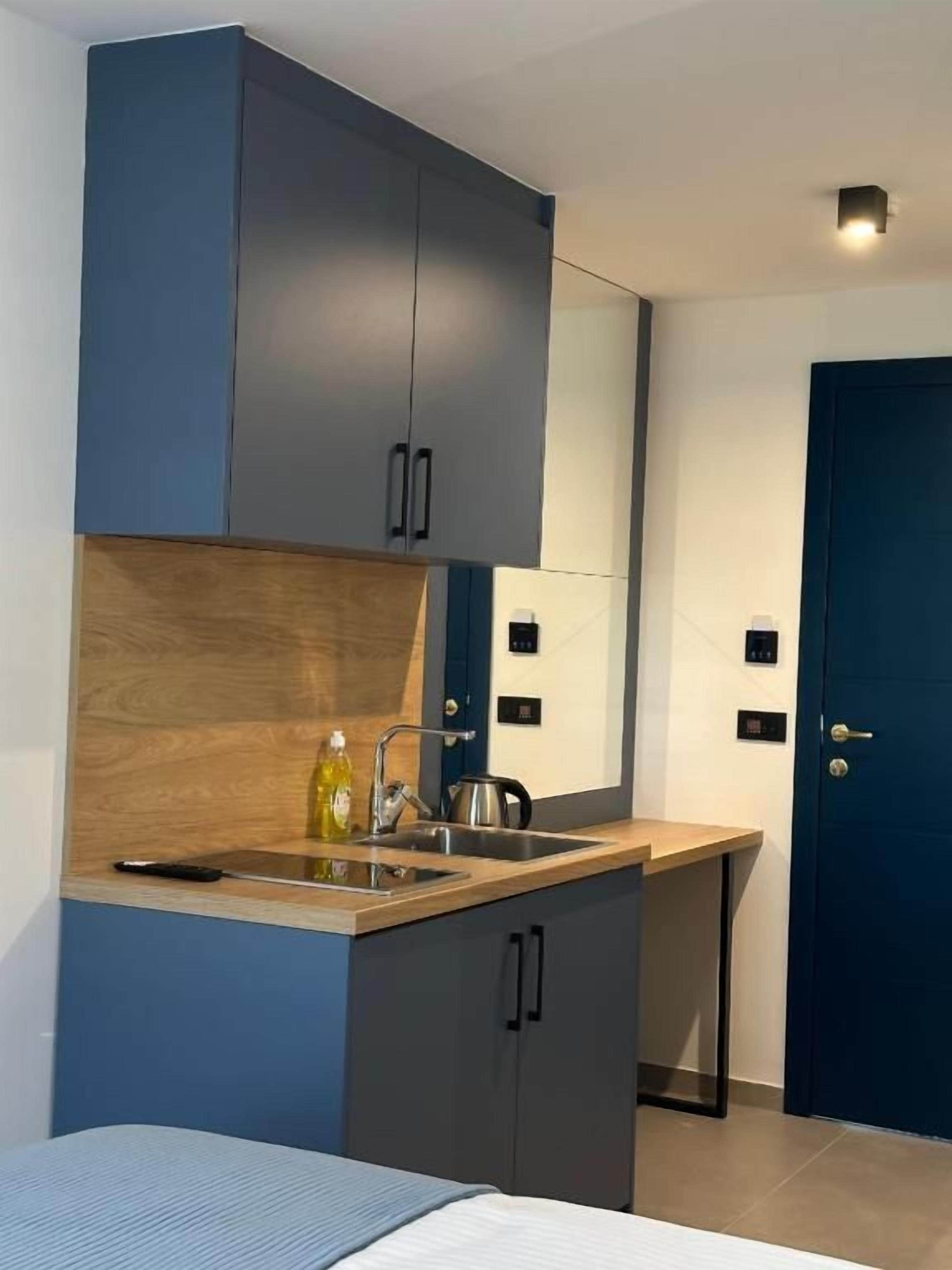 Cocina compacta con alacenas oscuras, encimera de madera, un lavabo y una puerta.