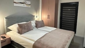 A bedroom with a bed, bedside table, nightstand, and a wardrobe. - Alinar Oasis Budget Hotel (Sarajevo)