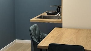 A small kitchenette with a wooden countertop, a sink, and a chair. - Alinar Oasis Budget Hotel (Sarajevo)