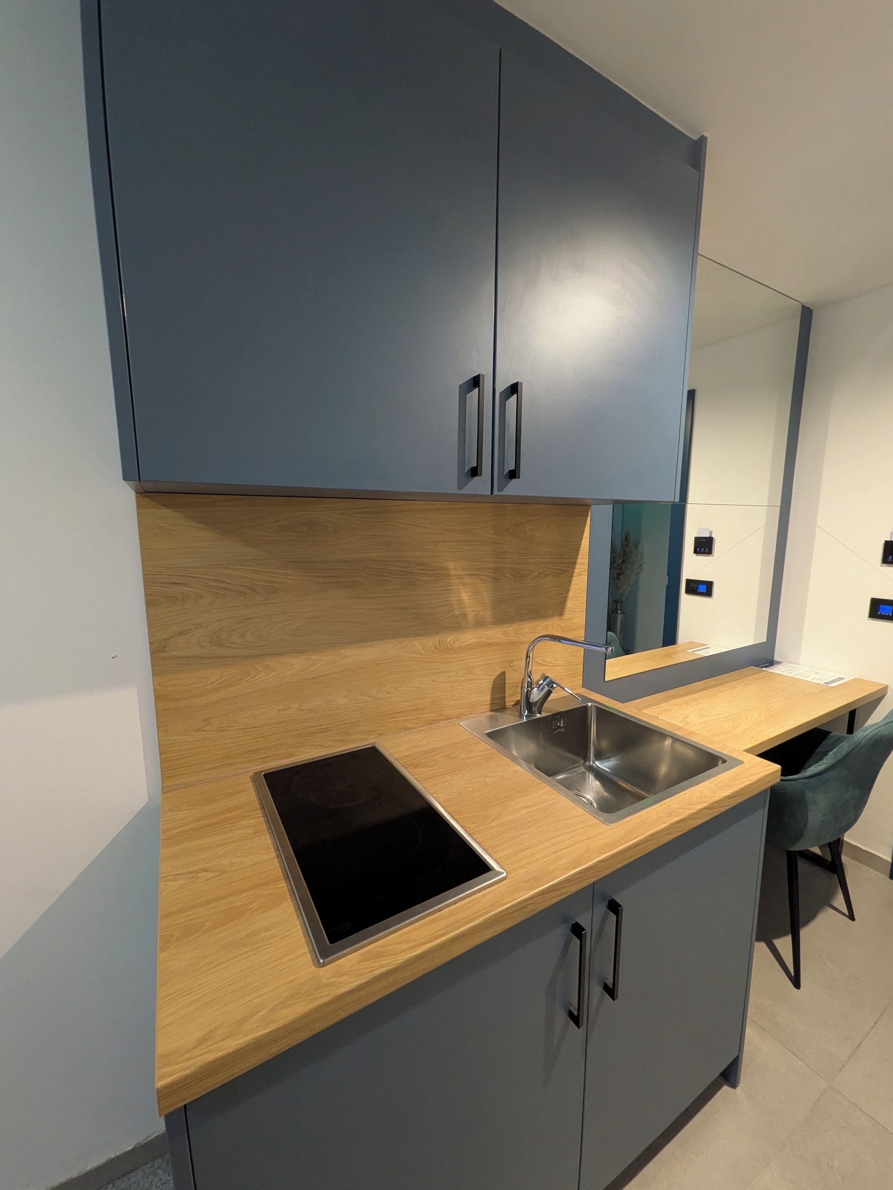 Una cocina moderna con gabinetes grises, encimera de madera, estufa integrada y un lavamanos.