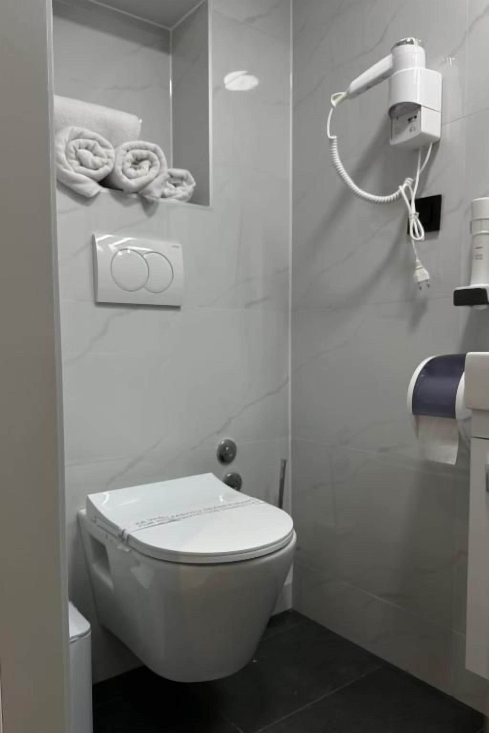 Une salle de bain équipée de toilettes, d’un porte-serviettes, d’un sèche-cheveux et d’un sèche-mains.